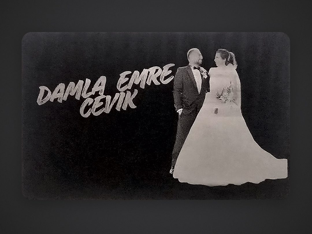 Studio photo of the engraved metal card showing Damla & Emre Çevik's wedding portrait